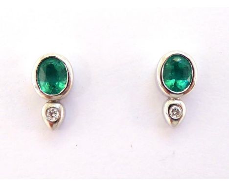 A pair of emerald and diamond ear studs, each stud set with an oval cut emerald, a small rub over set brilliant below, the em