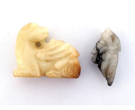 Two carved Chinese jade pendants in the Ming style, one a creamy colour in the form of a beast, and another smaller one in gr