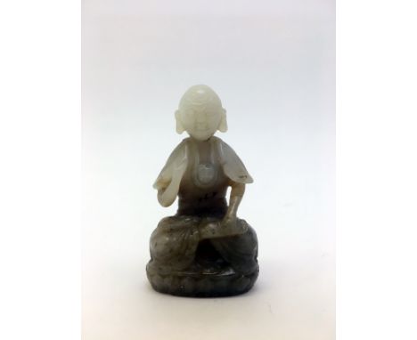 A Chinese carved jade figure of a seated dharma on lotus base, stone in partially white and brown tone, Qing period, 6.5cm hi