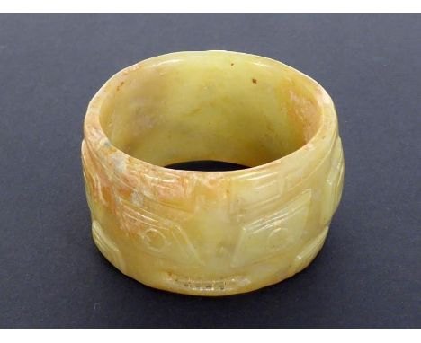 A Chinese archaic style yellow jade ring carved with masks and scrolls, with partial tan colour to surface. 19th century. Pro