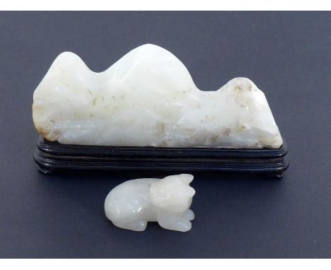 A Chinese carved celadon jade brush rest in the form of a mountain range on a carved wood stand, together with a jade attachm