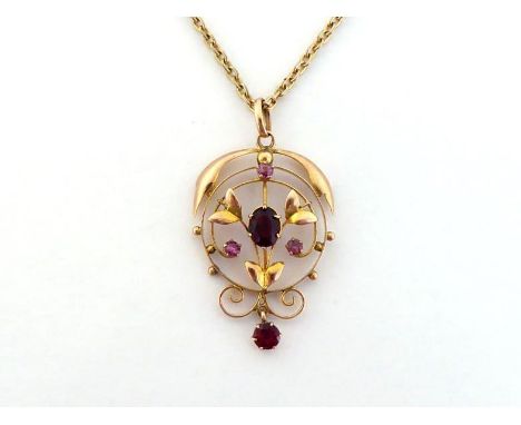 An Edwardian ruby and garnet pendant, the open work design set with oval and round cut garnets with small ruby accents, stamp