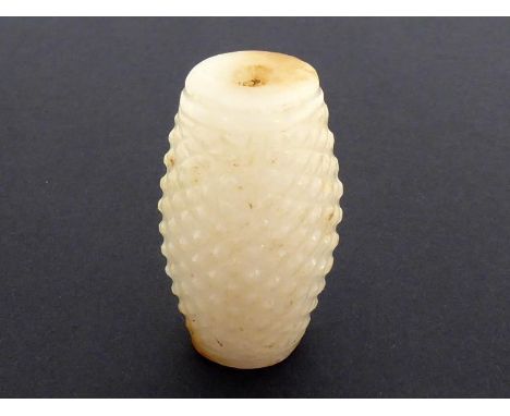 A Chinese white jade pendant of barrel form, carved with stylised “chi” dragons and occasional brown areas to the surface, 20