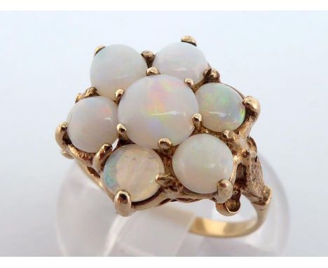 A 9 carat gold and opal cluster ring, the cluster of seven stones 15.7mm, the shank fully hallmarked, finger size O, 2.6gms C