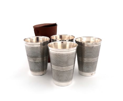 A set of four metalware stacking beakers, tapering circular form, engine-turned decoration, in a leather case, height 10.8cm.