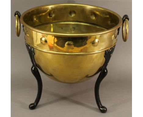 AN ARTS AND CRAFTS BRASS AND IRON PLANTER of dished circular form, with a moulded band of roundels between ring handles, rais
