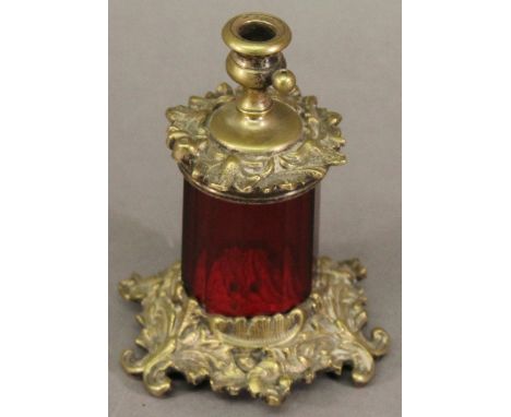 A VICTORIAN GILT METAL MOUNTED RUBY GLASS TAPER STICK HOLDER having a central socket within foliate moulding and faceted glas