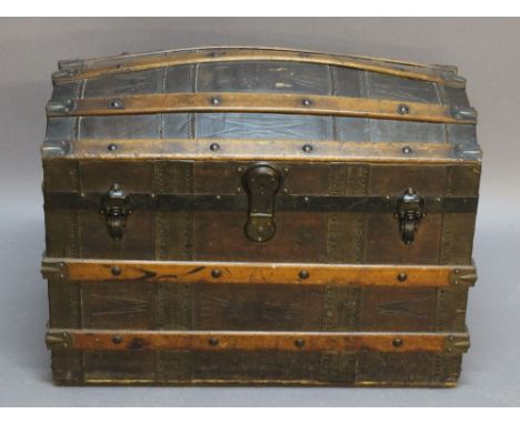 A LATE 19TH CENTURY DOMED AND RIBBED TRAVEL TRUNK, the brass mounted ribs intersected by tooled and studded leather, the inte