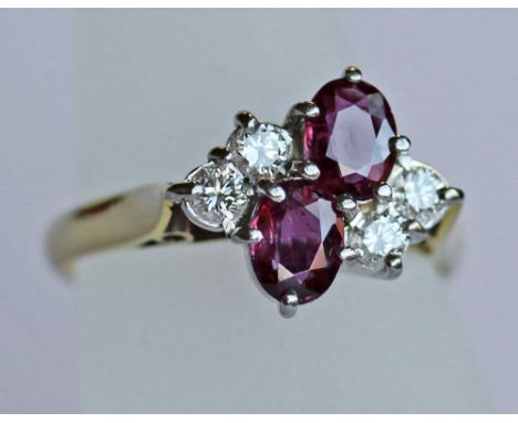 AN 18CT GOLD, DIAMOND AND RUBY SIX STONE RING having two central oval-cut rubies flanked by diamond brilliants to form a clus