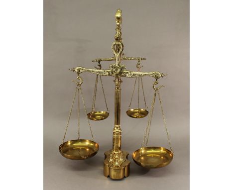 A SET OF DOUBLE BRASS BALANCE SCALES having fish-form beams, brackets and supports, reeded columns and a shaped ovoid base wi