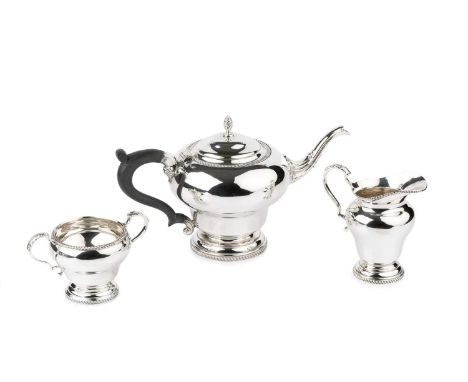 A silver three piece tea service, of shaped circular design with gadrooned borders, the teapot with pinecone finial and eboni