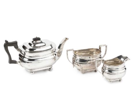 A George V silver three piece tea service, of shaped design on ball feet, the teapot with ebonised handle and knop, by Willia