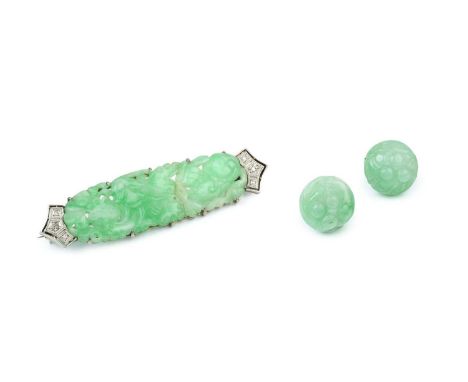 A jade and diamond panel brooch, the elongated shaped oval jadeite panel with pierced and carved decoration, enclosed by sing