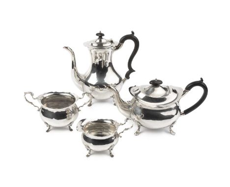 A George V silver four piece tea and coffee service, the tea pot and coffee pot with ebonised handles and knops, on shaped fe