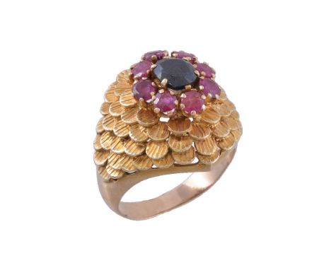 A 1970s ruby and sapphire dress ring, the bombé textured panel with a central round cut ruby and oval cut sapphire cluster, s