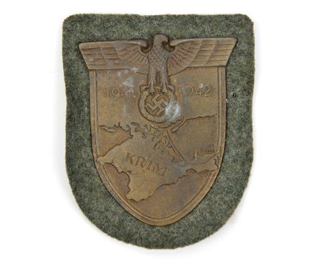 A Third Reich Krim shield, on field grey patch with paper backing. GC unissued (small patch of corrosion).  