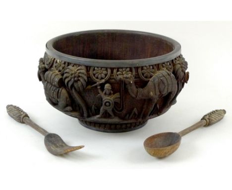 A Persian carved circular wooden bowl, early 20th century, decorated in high relief and poker work with a continuous frieze o