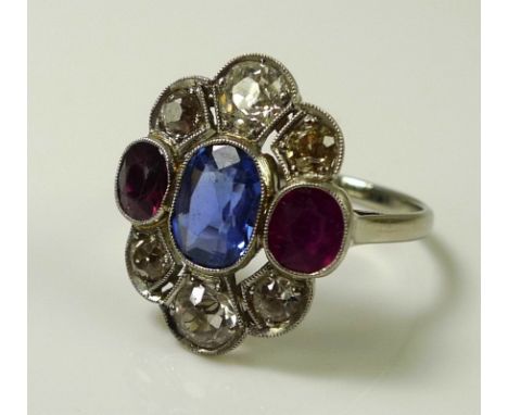 An 18ct white gold, blue sapphire, white sapphire, diamond and ruby dress ring, early to mid 20th century, central cornflower