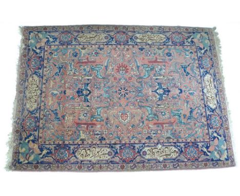 A fine antique Persian Kirman carpet, with Arabic poem woven to six medallions in the wide dark blue border, pink ground deco