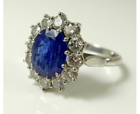 An 18ct white gold, sapphire and diamond ring, the large dark cornflower blue oval sapphire 8mm by 7.5mm, surrounded by twelv