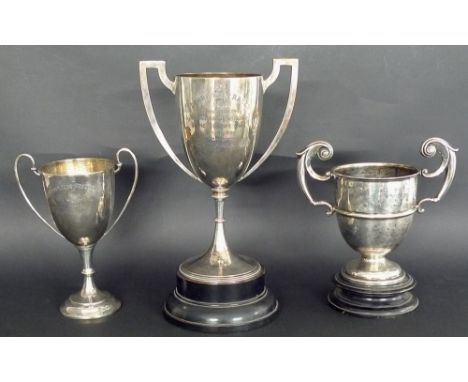 Three Edwardian silver trophies, the first with two angular handles framing elongated body, beaded knops to stem and conformi