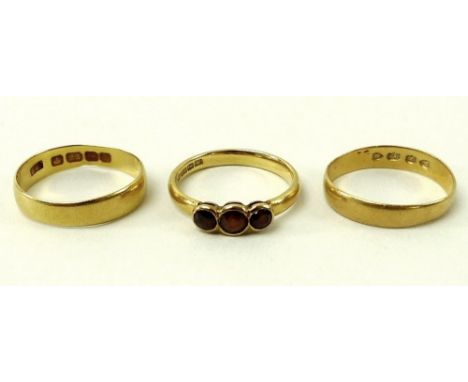 A group of three 22ct gold rings, comprising two wedding bands, size K, and size L, and a three stone ring, size M, 7.8g tota