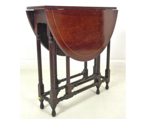 An Edwardian mahogany Sutherland table, circular drop leaf surface with fan paterae and line border, turned supports and stre