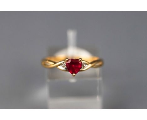 A yellow gold dress ring set with a heart cut synthetic ruby and two single cut diamonds. Yellow shank. Hallmarked 9ct gold, 