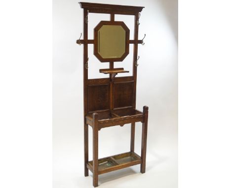 An early 20th century oak hall stand, central octagonal mirror with undershelf, brass hooks to either side, stick stand base 