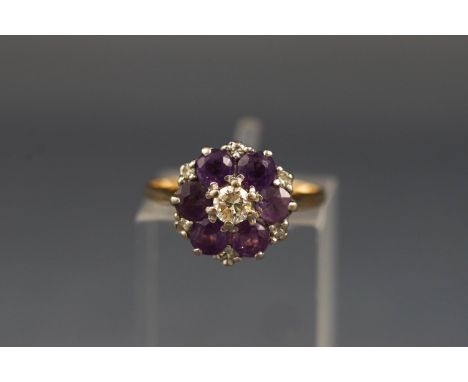 A gold, amethyst and diamond cluster ring, centred with a round brilliant diamond approx. 0.16cts, claw set within a round mi