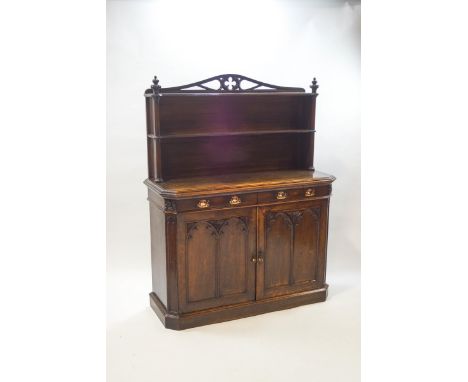 A Victorian oak Gothic chiffonier, the two shelf rack with trefoil carved crest rail and octagonal pillar supports, over two 