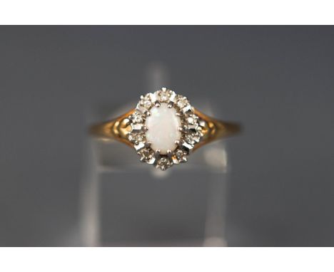 A yellow and white gold cluster ring set with an oval cabochon opal and ten single cut diamonds. Hallmarked 9ct gold, London.