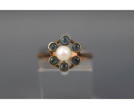 A yellow gold cluster ring set with a single pearl and six round aquamarines. Tests indicate 18ct gold. Size M. 2.9 grams