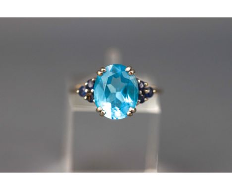 A white gold dress ring set with an oval blue topaz and six round cut sapphires. Hallmarked 9ct gold, Birmingham. Size: M. 3.