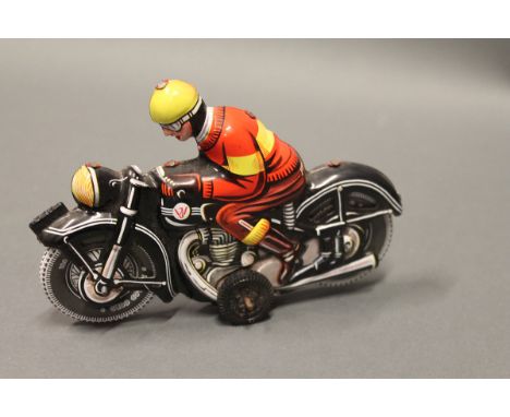 A WJ (West Germany) tinplate motorbike and rider - black coloured motorbike, red coloured clothing and yellow helmet