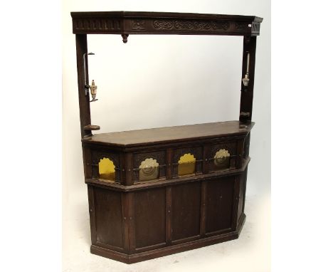 An early 20th century oak freestanding bar, the base with glazed top section with carved surround above five panelled front, 