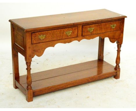 A reproduction oak potboard dresser base with two drawers raised on ring turned supports.