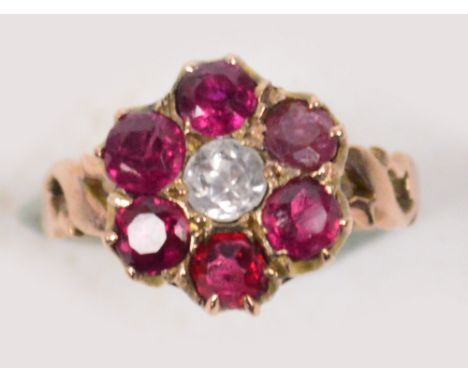 A yellow metal floral dress ring, the central white topaz surrounded by red topaz (one replaced), with pierced shoulders, siz