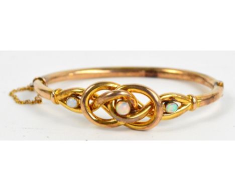 A 9ct yellow gold snap bangle set with three opals within a knot design, approx 9.6g. CONDITION REPORT: Edwardian in age. Min