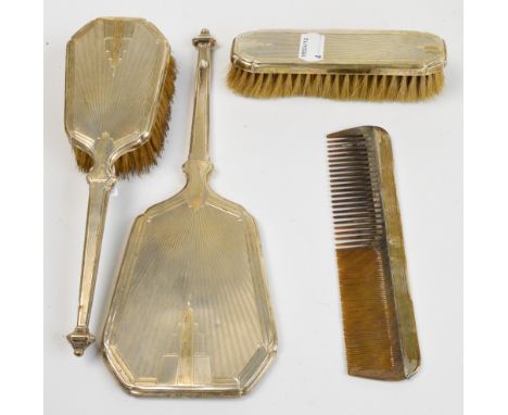 A George V hallmarked silver Art Deco four piece dressing table set comprising a hand mirror, a clothes brush, a hair brush a