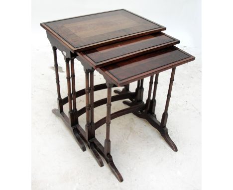 An Edwardian nest of three mahogany broad crossbanded rectangular occasional tables raised on ring turned end supports and sq