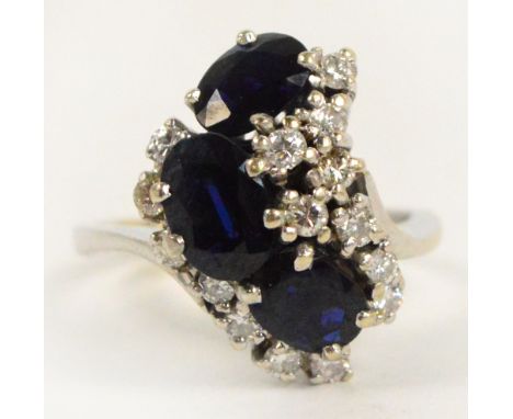 An 18ct white gold sapphire and diamond fancy cluster ring, the curved cluster head set with three oval cut sapphires surroun