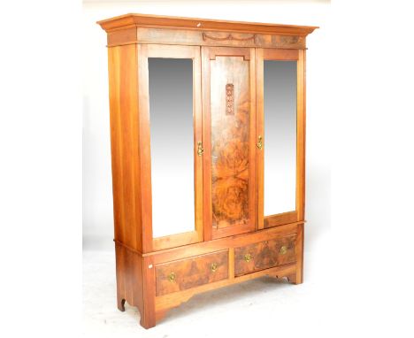 An Edwardian mahogany and walnut wardrobe with moulded cornice above pair of bevelled mirrored doors above two base drawers o