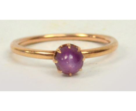 An unmarked yellow metal ring set with a star ruby cabochon in claw mount.