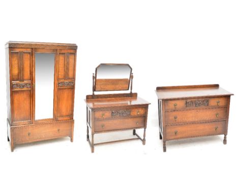 An early 20th century oak three piece bedroom suite comprising mirror door wardrobe with drawer to base, chest of three drawe