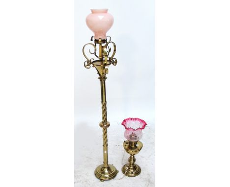 A decorative brass standard lamp, with scroll supports and wrythen twist knopped central column to a circular base, with pink