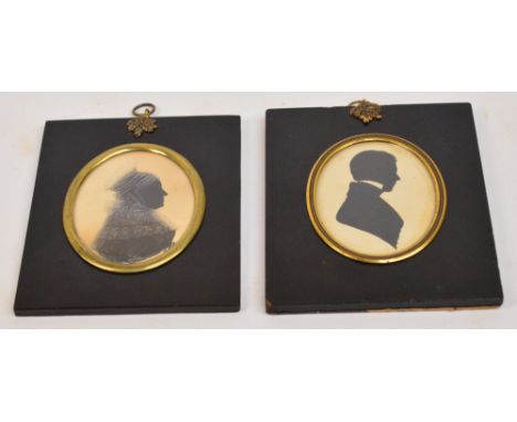 Two early 19th century oval portrait silhouettes depicting a gentleman and a lady wearing lace shawl, both in ebonised frames