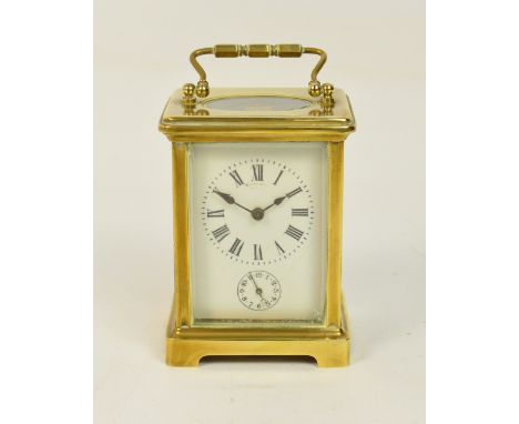 A late 19th century French brass striking carriage clock with four glass panels and an oval panel to the top, the white ename