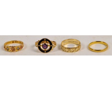 A 10ct yellow gold ring centred with an amethyst coloured stone surrounded by a black enamel band with pierced chevron decora