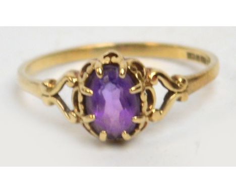 A 9ct yellow gold ring set with oval amethyst coloured claw set stone with pierced shoulders, size M.